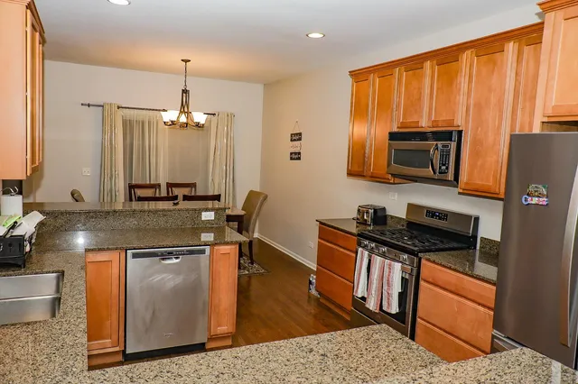 a kitchen with stainless steel appliances granite countertop a stove a sink and a microwave