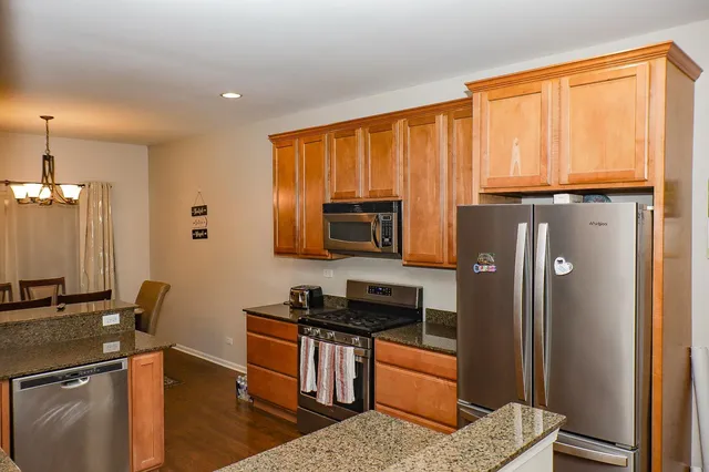 a kitchen with stainless steel appliances granite countertop a refrigerator and a stove top oven
