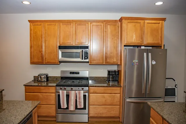 a kitchen with stainless steel appliances granite countertop a refrigerator and a stove top oven