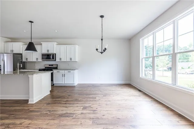 a kitchen with stainless steel appliances granite countertop a sink a stove a refrigerator and white cabinets