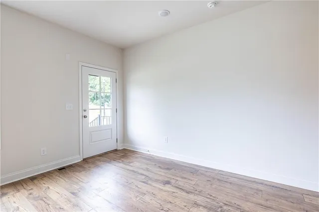 an empty room with wooden floor and windows