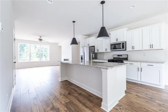 a open kitchen with white cabinets and wooden floor