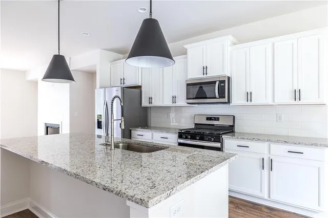 a kitchen with stainless steel appliances granite countertop a sink a stove and a microwave