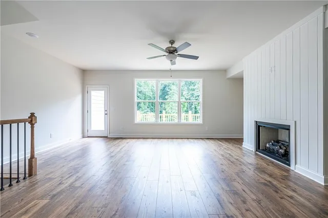 an empty room with windows fireplace and wooden floor