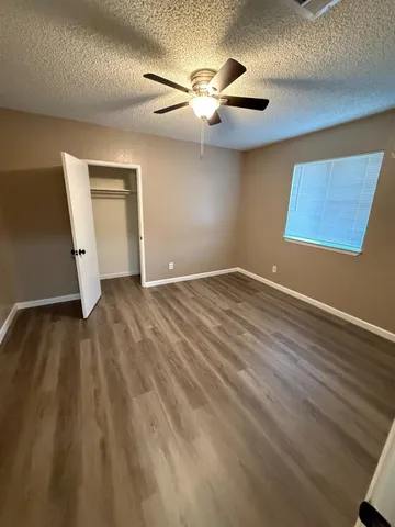 an empty room with wooden floor and a ceiling fan