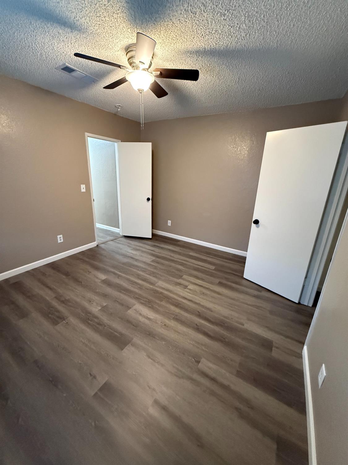 460 South Dearing Avenue Fresno, CA 93702 - Photo 12 of 23 an empty room with wooden floor and a ceiling fan