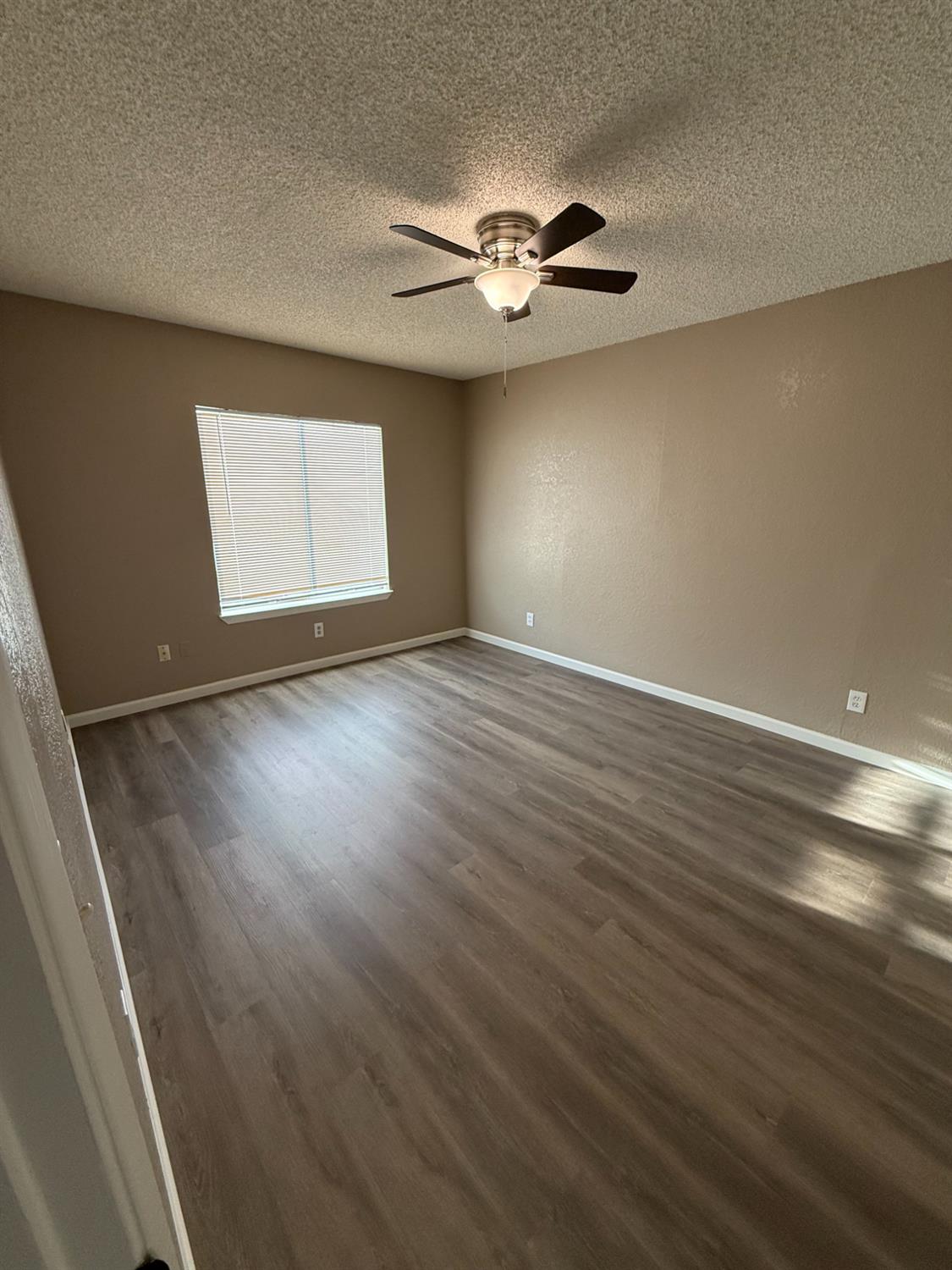 460 South Dearing Avenue Fresno, CA 93702 - Photo 18 of 23 an empty room with wooden floor chandelier fan and windows