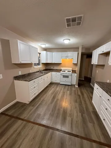a large kitchen with a large counter top space a sink stainless steel appliances and cabinets