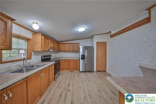 a large kitchen with stainless steel appliances granite countertop a lot of counter space and wooden floors