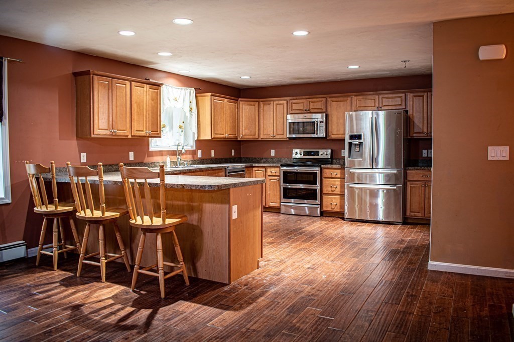 227 Turkey Hill Road Rutland, MA 01543 - Photo 4 of 30 a kitchen with stainless steel appliances granite countertop a stove top oven a refrigerator and island with wooden floor