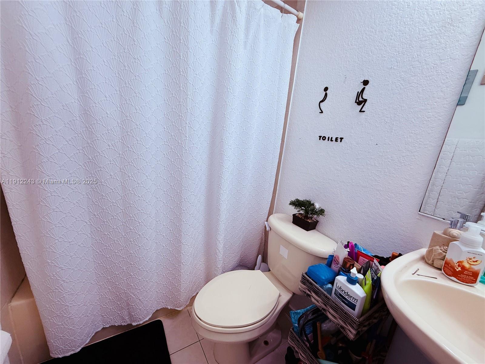 2243 Northwest 135th Terrace, Unit 2243 Opa-Locka, FL 33054 - Photo 16 of 19 a bathroom with a sink toilet and a mirror