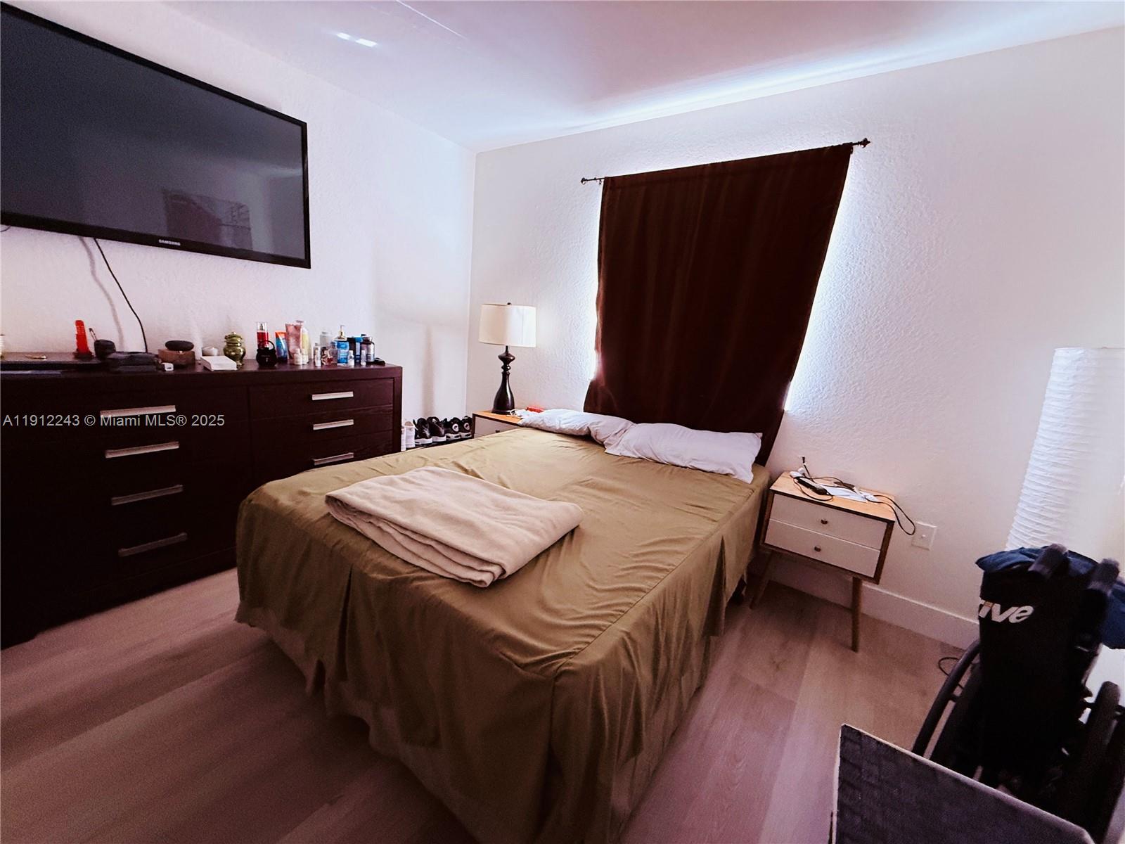 2243 Northwest 135th Terrace, Unit 2243 Opa-Locka, FL 33054 - Photo 4 of 19 a bedroom with a bed and a flat screen tv