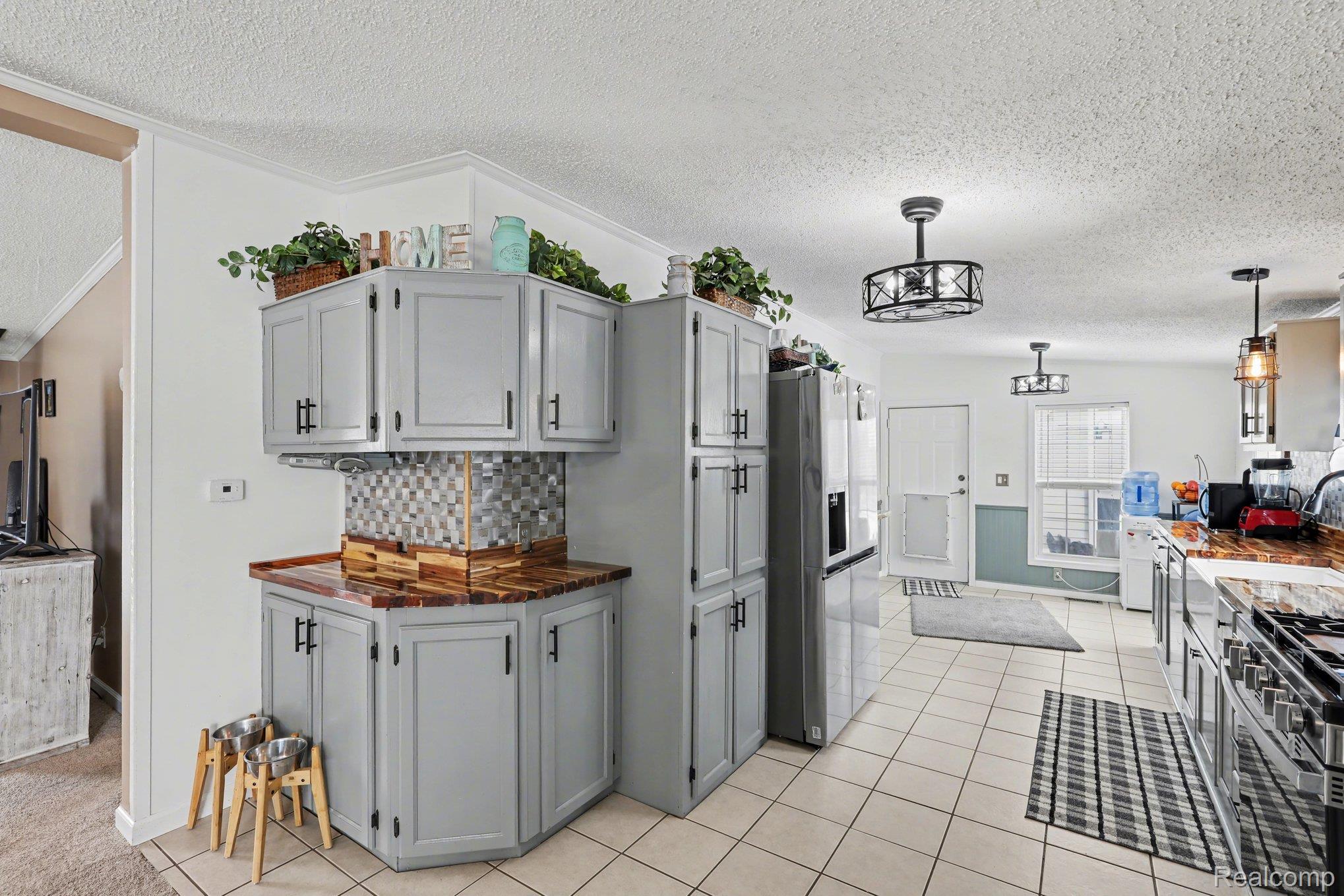 4458 Palms Road Casco, MI 48064 - Photo 13 of 32 Kitchen with gray cabinetry, stainless steel appliances, a textured ceiling, backsplash, and decorative light fixtures