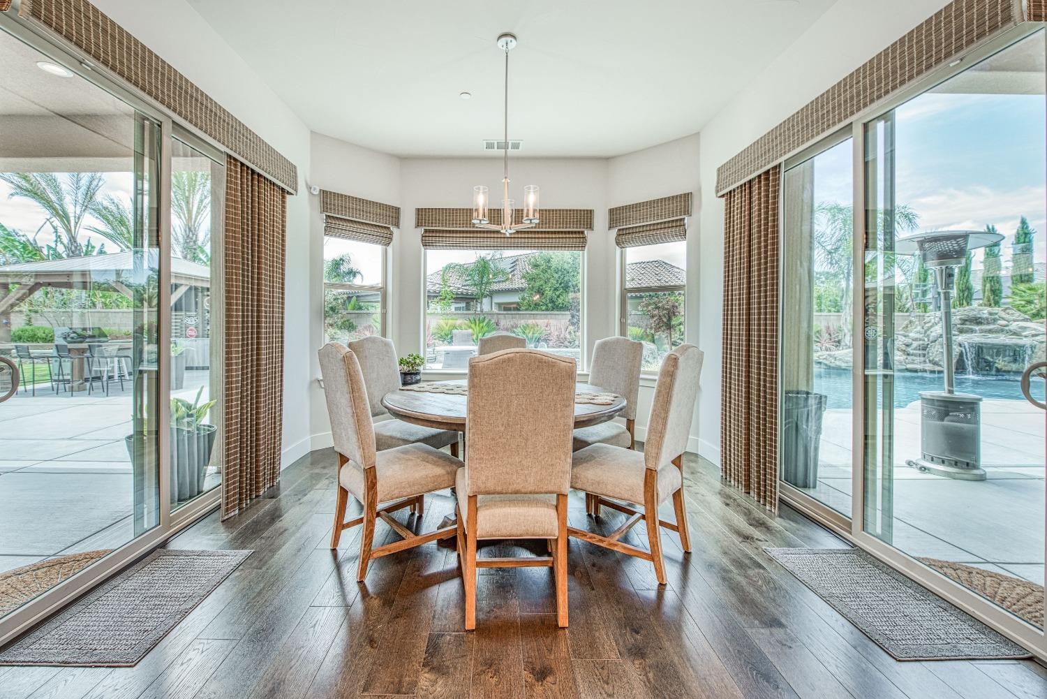 1632 North De Wolf Avenue Clovis, CA 93619 - Photo 42 of 80 a dining room with wooden floor a chandelier a glass table and chairs