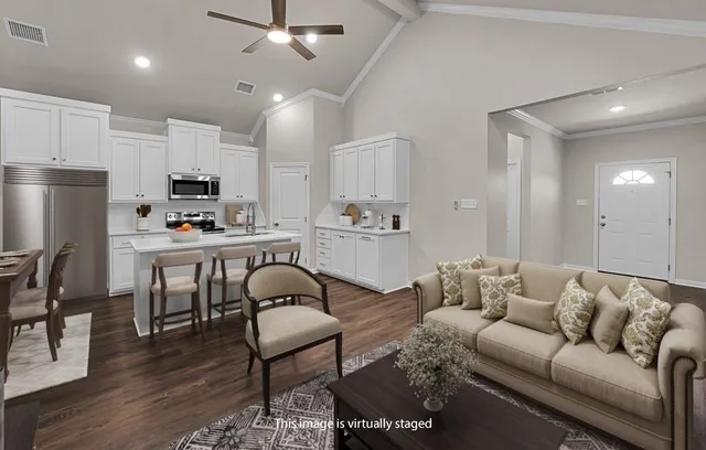 a living room with stainless steel appliances furniture a rug and a kitchen view