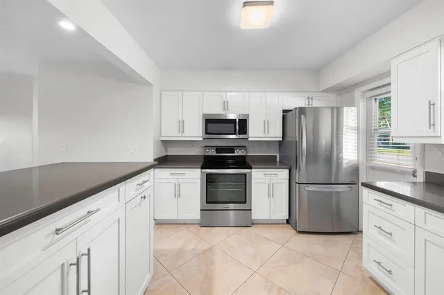 a kitchen with granite countertop a refrigerator and a stove top oven