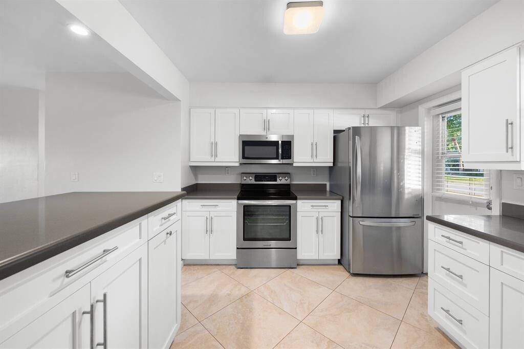 a kitchen with granite countertop a refrigerator and a stove top oven