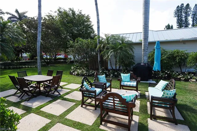 a view of a patio with table and chairs potted plants and palm tree