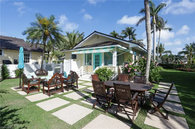 a view of a patio with table and chairs potted plants and palm tree