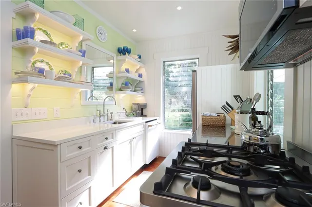 a kitchen with a sink appliances cabinets and a large window