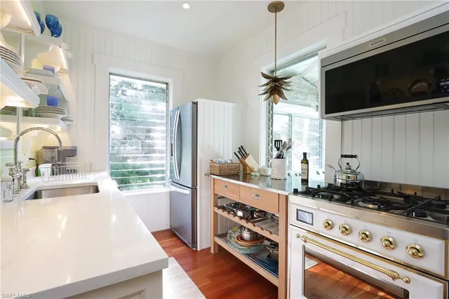 a kitchen with a stove a sink and a flat screen tv