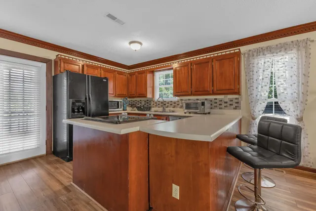 a kitchen with stainless steel appliances granite countertop a refrigerator a stove and a sink with wooden cabinets