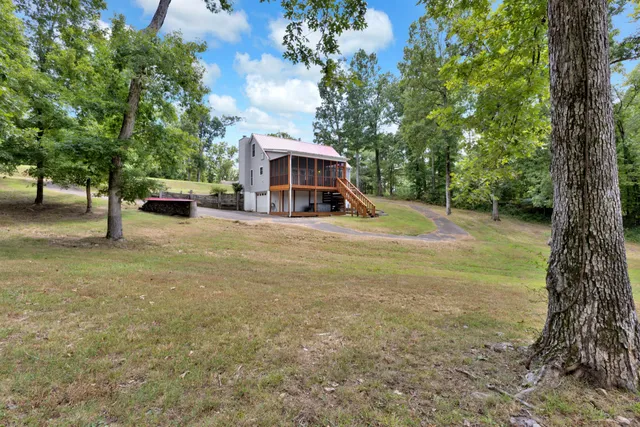 a view of a house with a yard and large trees