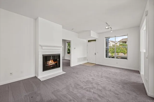 an empty room with windows and fireplace