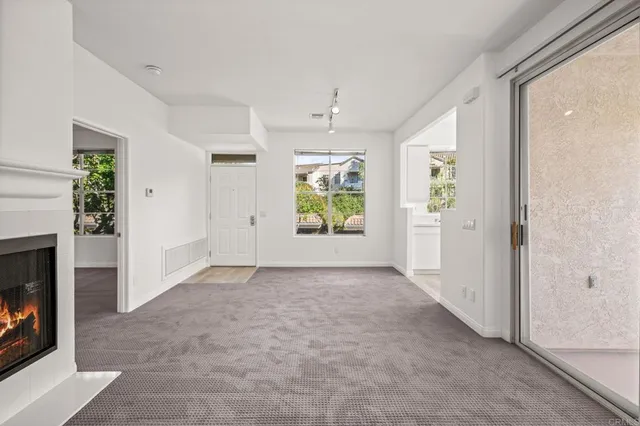 an empty room with windows and fireplace