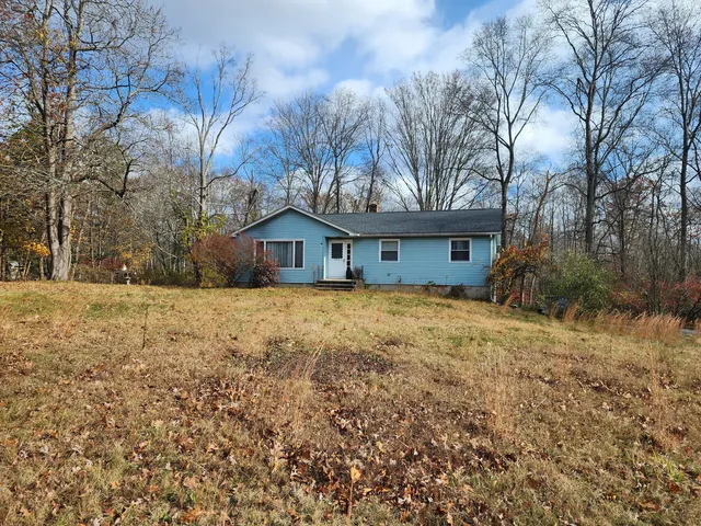 a front view of house with yard and trees around