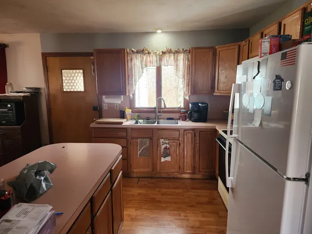 a kitchen with stainless steel appliances granite countertop a refrigerator a sink dishwasher a stove and white countertops with wooden floor