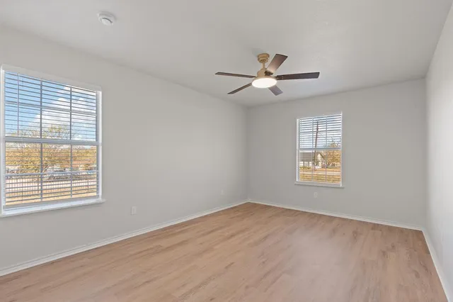 a view of empty room with wooden floor and fan