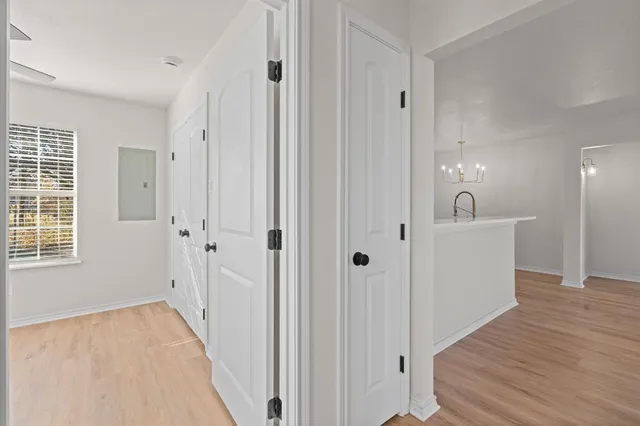 a view of a hallway with wooden floor and a bathroom