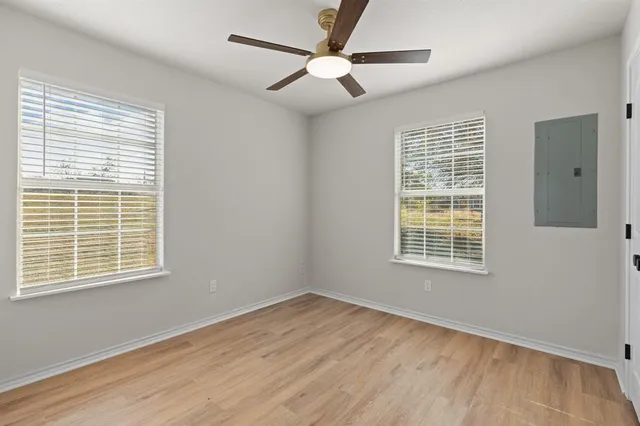 a view of an empty room with wooden floor and a window