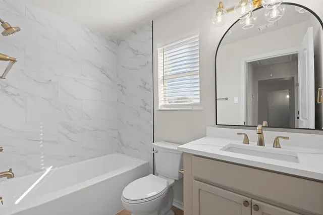 a bathroom with a granite countertop sink a toilet and bathtub