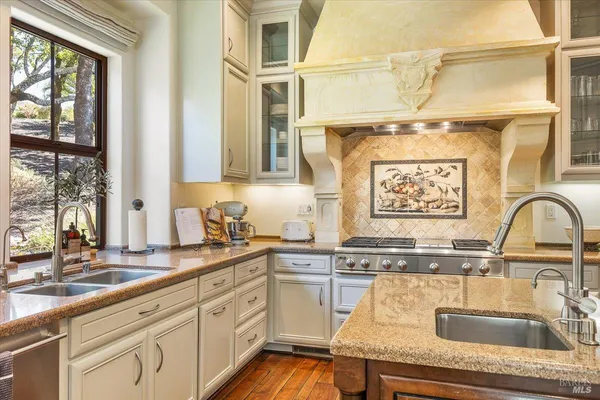 a kitchen with stainless steel appliances granite countertop a sink and a stove next to a window
