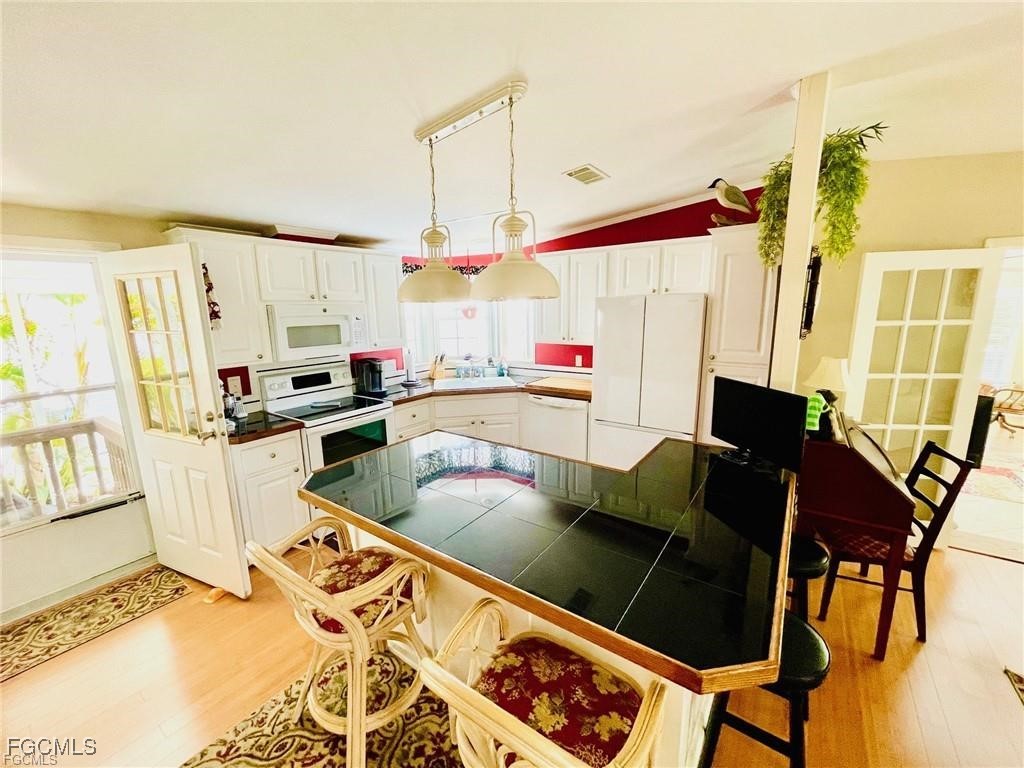 3064 Sloop Lane St. James City, FL 33956 - Photo 14 of 30 a kitchen with stainless steel appliances kitchen island granite countertop a table and chairs in it