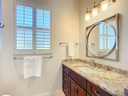 a bathroom with a granite countertop toilet a sink and a mirror