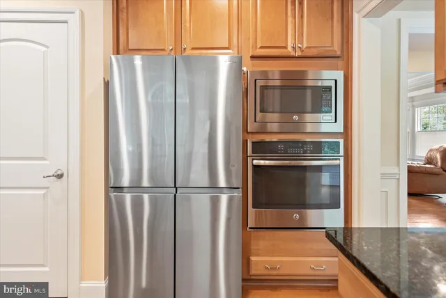 a kitchen with stainless steel appliances granite countertop a sink a stove a refrigerator a washer and dryer with wooden floor