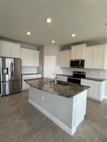 a large kitchen with granite countertop a lot of counter space cabinets and stainless steel appliances