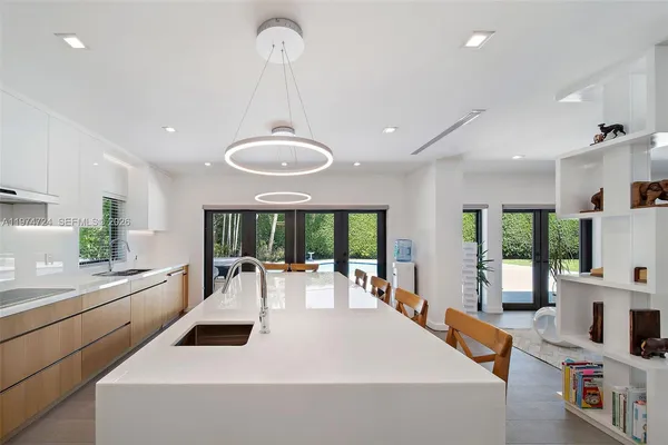 a large white kitchen with a large window appliances and cabinets