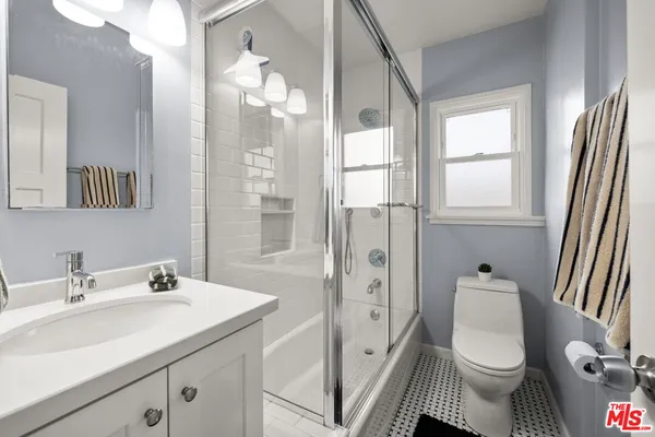 a bathroom with a sink a toilet a mirror and shower