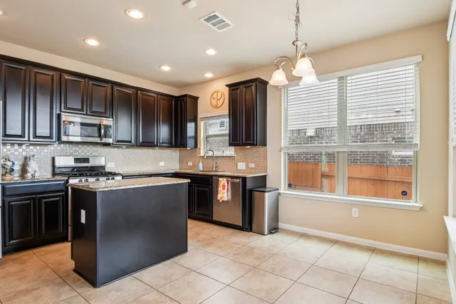 a kitchen with kitchen island granite countertop a stove and a sink
