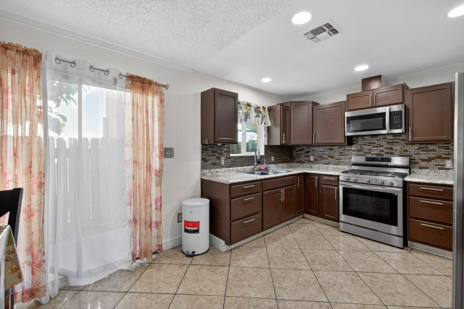 13591 East 5th Street Parlier, CA 93648 - Photo 12 of 31 a kitchen with stainless steel appliances granite countertop a refrigerator and a stove top oven