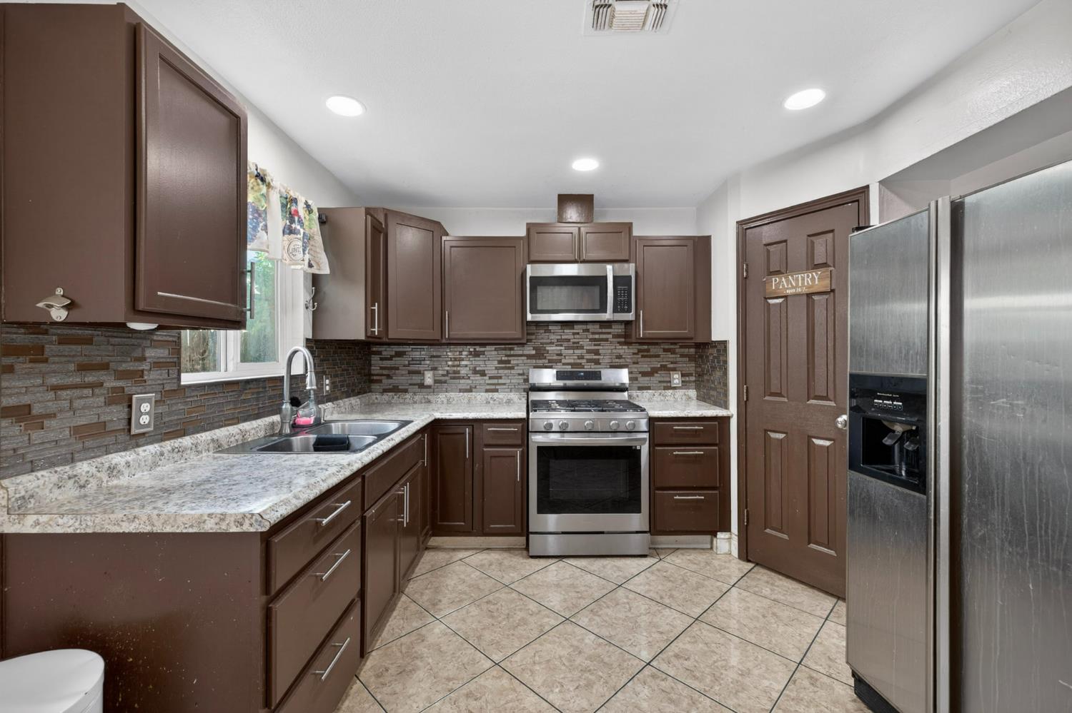 13591 East 5th Street Parlier, CA 93648 - Photo 13 of 31 a kitchen with stainless steel appliances granite countertop a sink stove and refrigerator