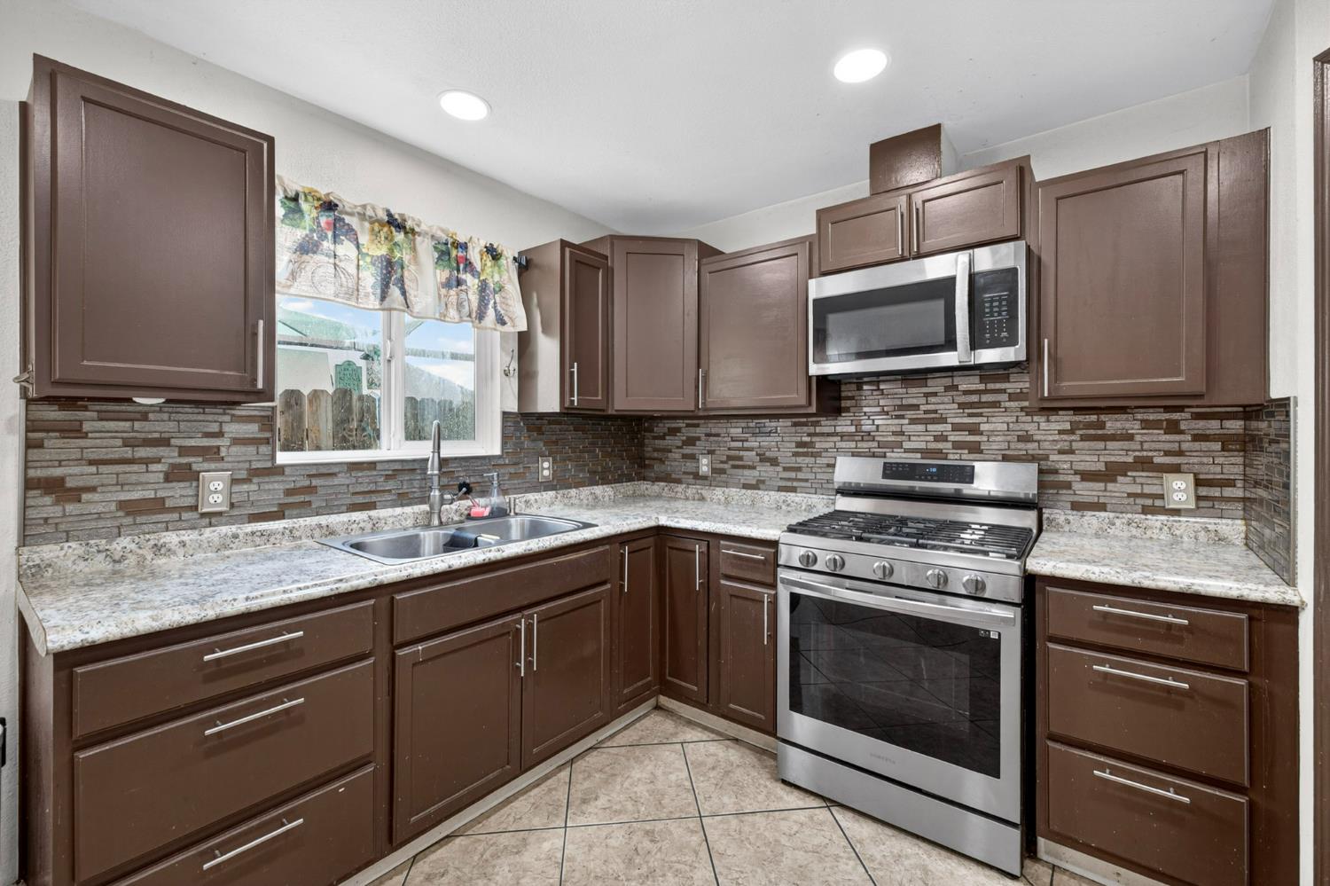 13591 East 5th Street Parlier, CA 93648 - Photo 14 of 31 a kitchen with stainless steel appliances granite countertop a sink stove microwave and cabinets