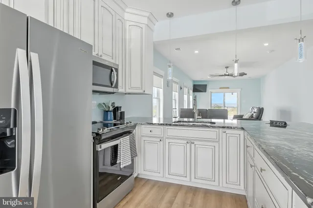 a kitchen with stainless steel appliances granite countertop a stove top oven a sink dishwasher and white cabinets with wooden floor