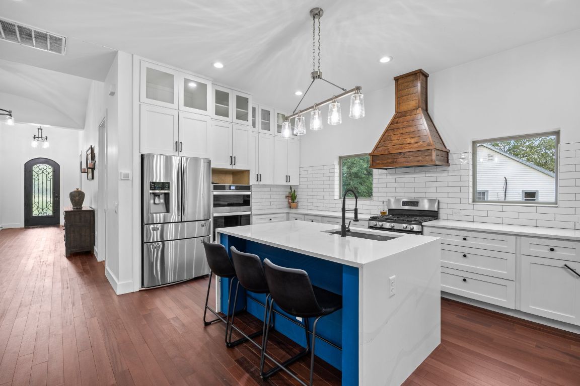 390 Riddle Road Cedar Creek, TX 78612 - Photo 8 of 27 a kitchen with refrigerator cabinets and wooden floor