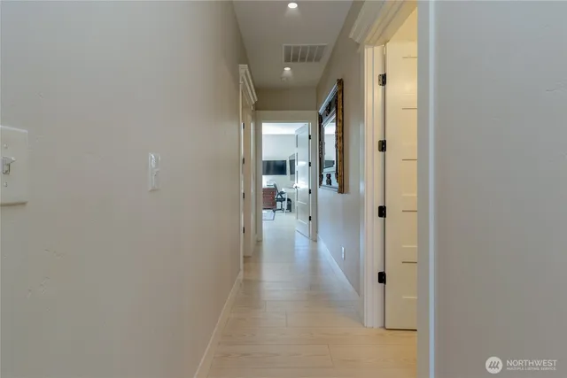 a view of a hallway with wooden floor and a bathroom