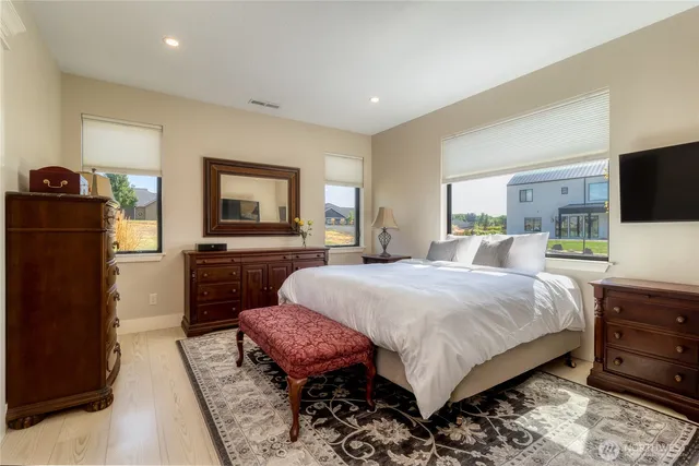 a spacious bedroom with a bed and a flat screen tv